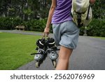 A woman is rollerblading gracefully on a road located in a park