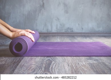 Woman rolling her mat after a yoga class