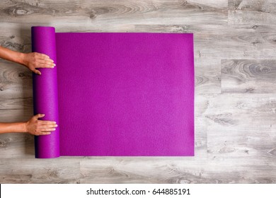 Woman rolling her Yoga mat after a workout - top view