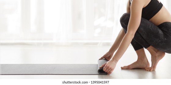 Woman Rolling Mat After Yoga Training In White Studio, Copy Space, Panorama