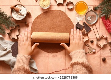 Woman rolling out gingerbread dough for Christmas cookies on pink tile background - Powered by Shutterstock