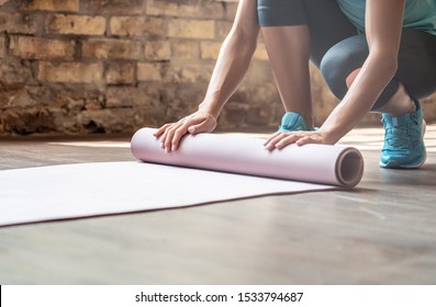 Woman rolling yoga pilates rubber mat on gym studio floor, female fit sporty lady preparing for sport workout exercise fitness class close up view, training routine equipment background concept - Powered by Shutterstock