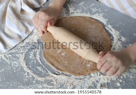 A woman rolls out the baking dough with a wooden rolling pin. Top view. Concept: homemade cakes. Selective focus