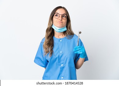 Woman Romanian dentist holding tools over isolated on pink background and looking up