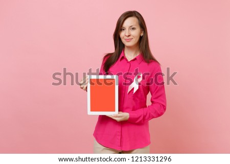 Woman in rose clothes with pink silk ribbon hold tablet pc isolated on pastel wall background, studio portrait. Medical healthcare gynecological oncology, Breast Cancer Awareness concept Mock up area
