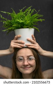 Woman In Round Glasses With Room Flower On Her Head. Close Up. Girl Nerd Geek. Green Indoor Plant. Vertical Frame