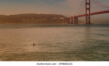 A Woman Rower In The Bay In The Early Morning Below The Golden Gate Bridge Having A Workout