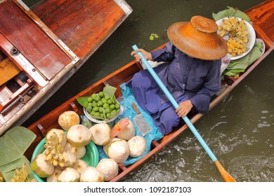 Woman rowing a Coconut juice boat in floating market, Damnoen Saduak District near Bangkok, Ratchaburi, Thailand.