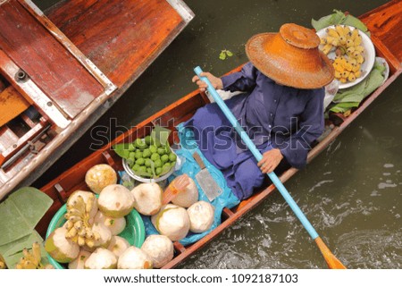 Woman rowing a Coconut juice boat in floating market, Damnoen Saduak District near Bangkok, Ratchaburi, Thailand.