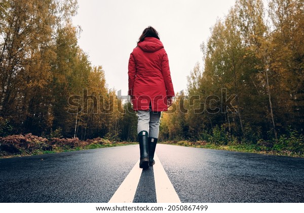 A woman\
in Rubber Boots Walks Along the White\
Line.