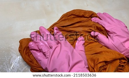 Woman in rubber cleaning gloves prepares to clean up her house using sponges, rags and cleaning products