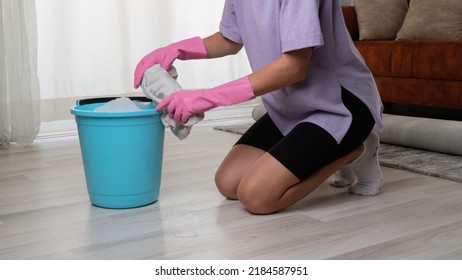 A woman in rubber gloves squeezes a rag in a bucket washes the floor - Shutterstock ID 2184587951