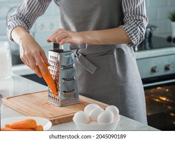 A Woman Rubs Carrots On A Grater To Make A Carrot Cake