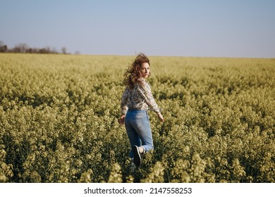 Woman run away through the flowering field and looking back