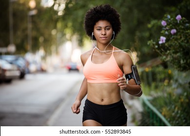 Woman runner in action. Listening to music through earphones.