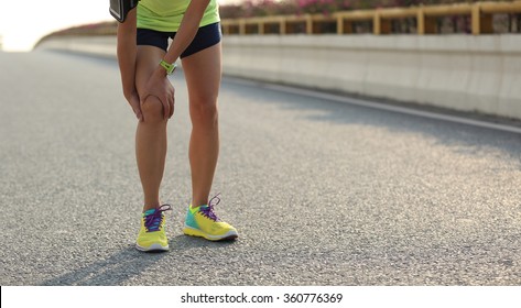 woman runner hold her injured leg on road
