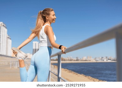 Woman runner jogger stretching leg physical exercise at river embankment closeup. Smiling sport active female jogging running training outdoor workout fitness admiring sunny waterfront scenery - Powered by Shutterstock