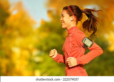 Woman runner running in fall autumn forest listening to music on smartphone using earphones. Female fitness girl jogging on path in amazing fall foliage landscape nature outside. - Powered by Shutterstock