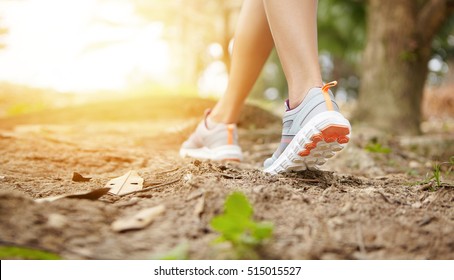 Woman Runner In Sneakers During Run On Trail In Forest. Cropped Rear View Of Female Jogger Running While Exercising Outdoors, Getting Prepared For Serious Marathon. Film Effect, Freeze Action Shot