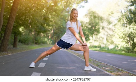 Woman runner stretching legs before exercising summer park   - Shutterstock ID 2247962707