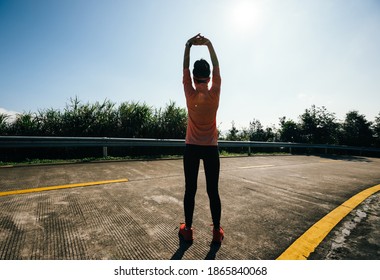 Woman Runner Warming Up On Mountain Top On Winter Day