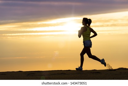 Woman running alone at beautiful sunset in the beach. Summer sport and freedom concept. Athlete training  on dusk. - Powered by Shutterstock