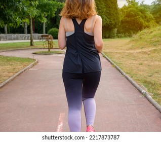 Woman Running Backwards In A Sunny Park. Running, Fitness And Lifestyle Concept.