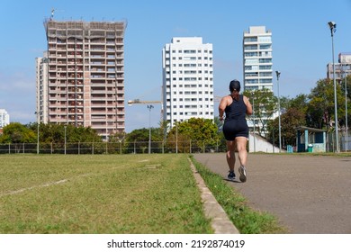 Woman Running Beside The City Football Field. Street Race. Amateur Sport Concept.