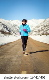 Woman Running Fast In Country Winter Mountain Road. Female Runner Training Endurance Outdoor In Cold Weather.