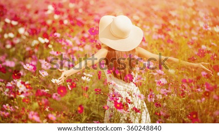 Woman running in the garden flowers Cosmos flowers to touch her. On a clear day