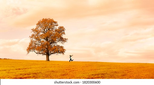 Woman running happily on a meadow with a tree in autumn