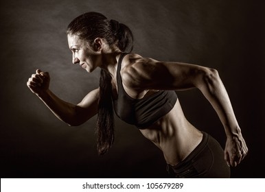 Woman Running On A Dark Background. Side View