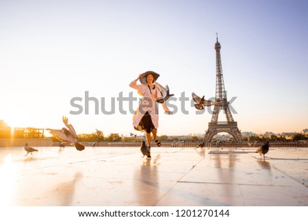 Woman running on the famous square dispersing pigeons with great view on the Eiffel tower early in the morning in Paris