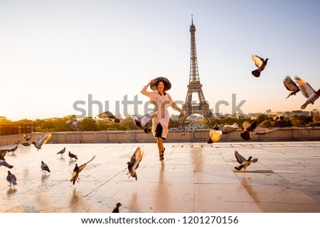 Woman running on the famous square dispersing pigeons with great view on the Eiffel tower early in the morning in Paris