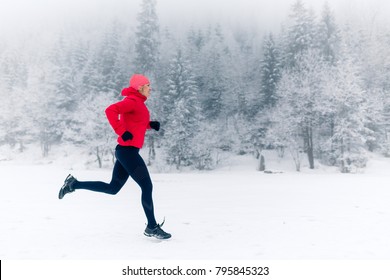 Woman Running On Snow In Winter Mountains. Sport, Fitness Inspiration And Motivation. Young Happy Woman Trail Running In Mountains On Snow, Winter Day. Female Trail Runner Jogging Outdoors.