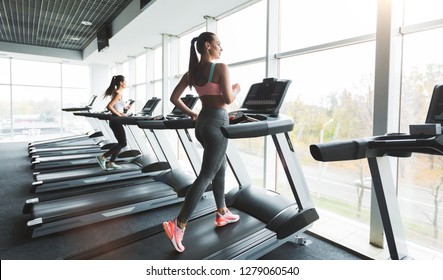 Woman running on treadmill at panoramic window, enjoying training in gym - Powered by Shutterstock