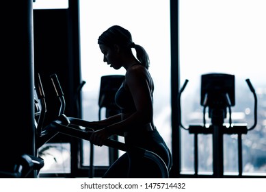 Woman running on the treadmill, silhouette shot, side view.