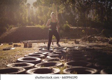 Woman running over tyres during obstacle course in boot camp - Powered by Shutterstock