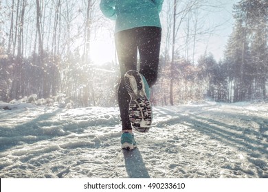 Woman Running At Snowly Winter Under Sunlight.