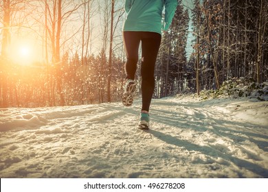 Woman Running At Snowly Winter Under Sunlight.