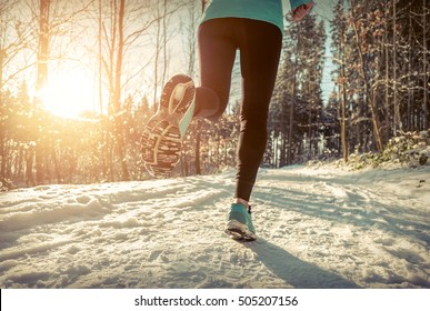 Woman Running At Snowly Winter Under Sunlight.