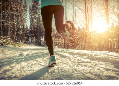 Woman Running At Snowly Winter Under Sunlight.