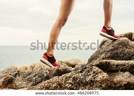 Woman running sport feet. Trail running marathon, fitness legs on rock and healthy summer lifestyle