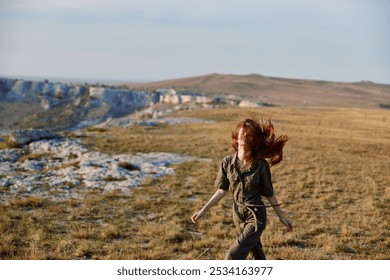 Woman running through grassy field with mountains in background serene landscape travel scene with redhaired beauty and nature - Powered by Shutterstock