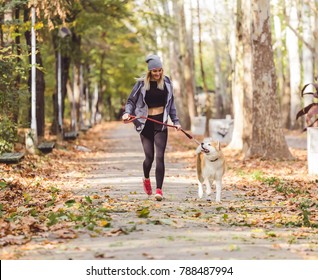 Woman Running And Walking In Beautiful Park With Akita Dog.