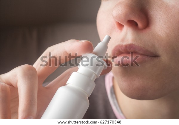 A woman with a runny nose holds a medicine in her\
hand, a red nose