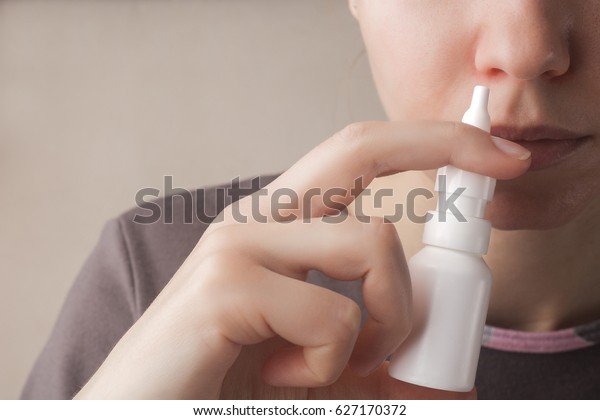 A woman with a runny nose holds a medicine in her\
hand, a red nose
