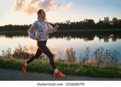 Woman runs in the park on autumn morning. Healthy lifestyle concept, people go in sports outdoors. Silhouette family at sunset. Fresh air. Health care, authenticity, sense of balance and calmness. - Shutterstock ID 2256606799