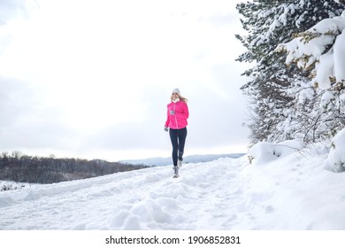 A Woman Runs In The Snow In The Winter Mountains. Sports, Fitness - Inspiration And Motivation. Woman Jogging Outdoors. High Quality Photo.