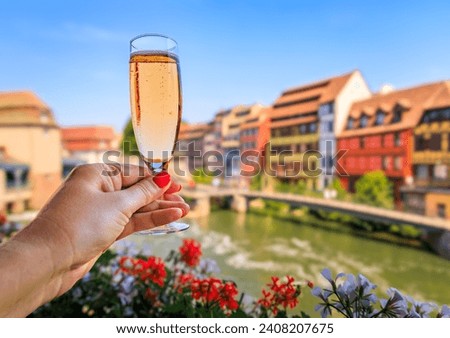 Woman s hand with a glass of Cremant sparkling wine at a winstub restaurant with flowers in the background, Petite France district, Strasbourg, France